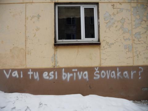 Läti keelne graffiti kollasel seinal tekstiga "vai tu esi briva šovakar?".